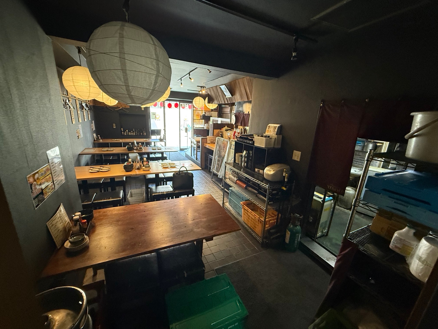 提灯と木製テーブル席が並ぶ居酒屋の内観
